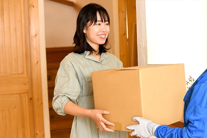 段ボールを配送業者に渡す女性